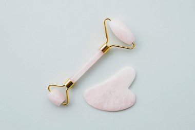 Pembe kuvarstan yapılmış yeşim taşı silindirli, lenfatik drenaj yüz masajı için doğal bir alet. Üst görünüm gri arkaplan, kopyala boşluk, kapat. Güzellik ve vücut bakımı.