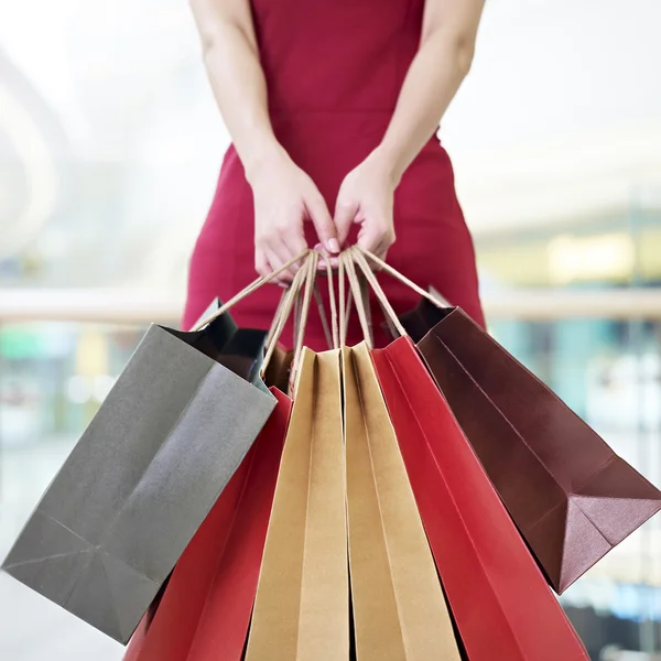 Jovem mulher carregando sacos de compras de papel no shopping moderno — Fotografia de Stock