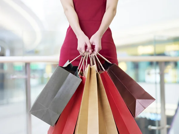 Mujer joven que lleva bolsas de compras de papel en el centro comercial moderno — Foto de Stock