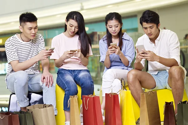 Jóvenes asiáticos jugando con teléfonos móviles — Foto de Stock