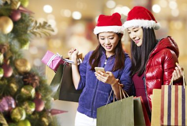 Noel alışveriş sırasında cep telefonu kullanan genç Asyalı kadınlar