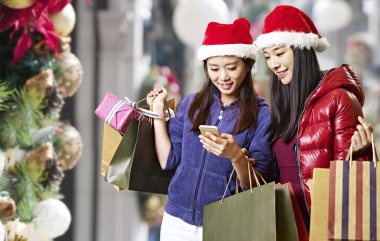 Noel alışveriş sırasında cep telefonu kullanan genç Asyalı kadınlar