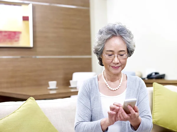 Senior Aziatische vrouw met behulp van mobiele telefoon — Stockfoto