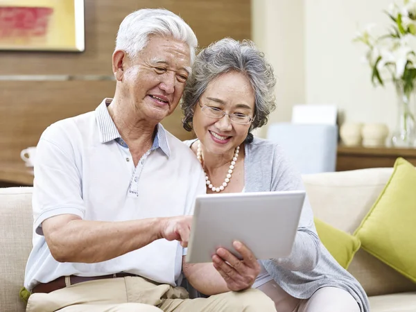 Sênior asiático casal usando um tablet computador juntos — Fotografia de Stock