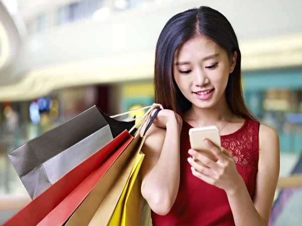 Giovane donna asiatica utilizzando il cellulare durante lo shopping — Foto Stock