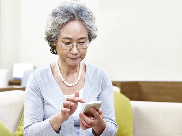 Старша азіатська жінка використовує мобільний телефон — стокове фото