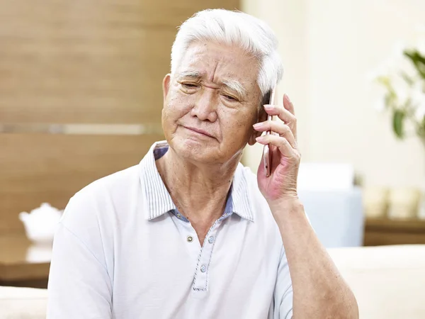 Unhappy senior asian man talking on phone — Stock Photo, Image