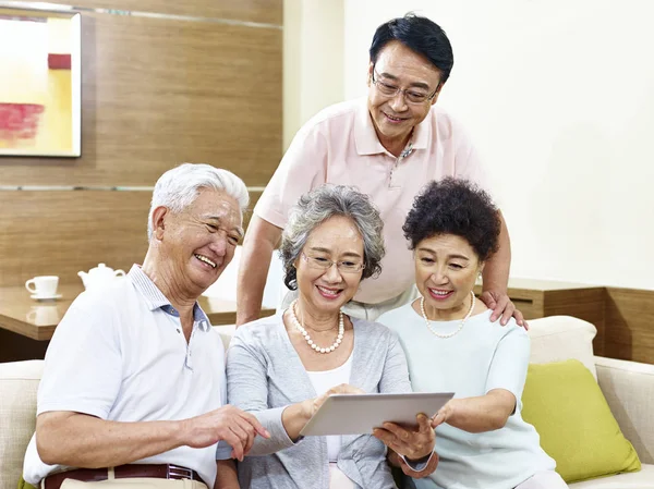 Two happy senior asian couples using tablet computer at home — Stock Photo, Image