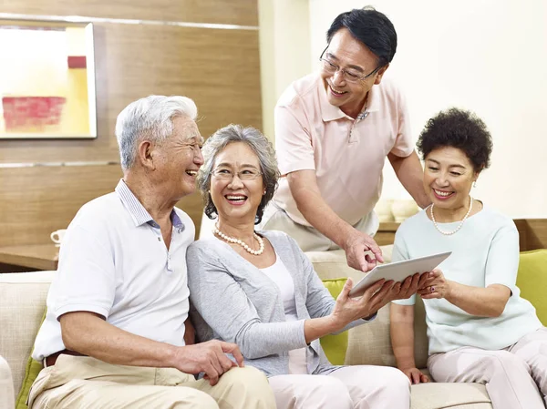 Two happy senior asian couples using tablet computer at home — Stock Photo, Image