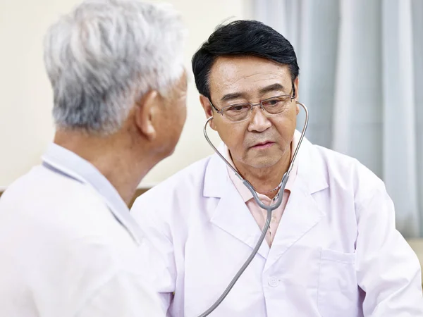 Medico asiatico controllando un anziano paziente — Foto Stock