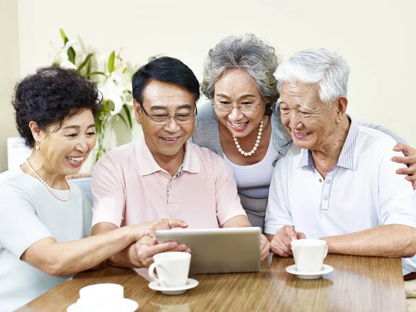 Две пожилые азиатские пары с помощью планшетного компьютера — стоковое фото