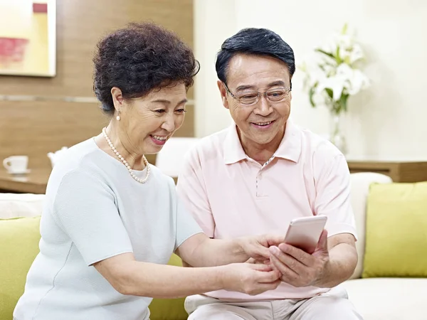 Пожилая азиатская пара с помощью мобильного телефона — стоковое фото