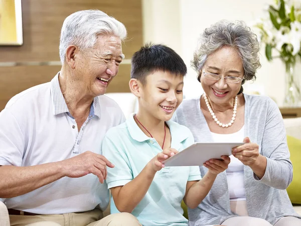 Asian grand parents and grand child using tablet at home — Stock Photo, Image