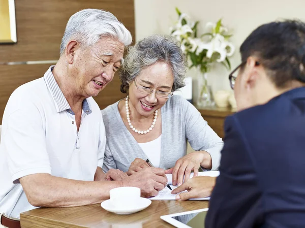 Старшая азиатская пара подписывает контракт — стоковое фото