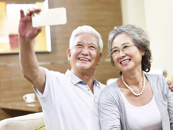Счастливая старшая азиатская пара делает селфи — стоковое фото