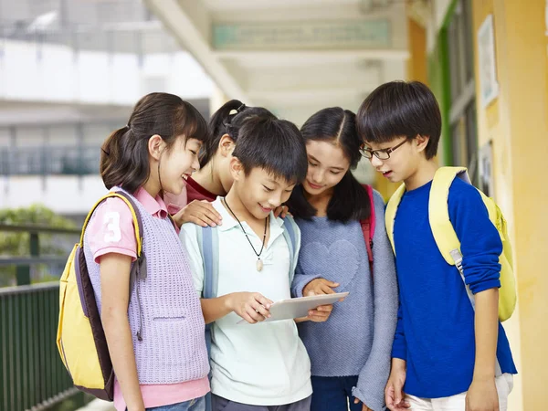 Группа азиатских учеников, использующих планшетный компьютер в школе — стоковое фото
