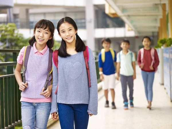 Азиатские школьницы, идущие по коридору — стоковое фото