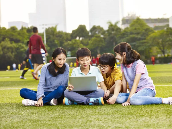 Aziatische basisschool jongens en meisjes zitten op Speeltuin gra — Stockfoto
