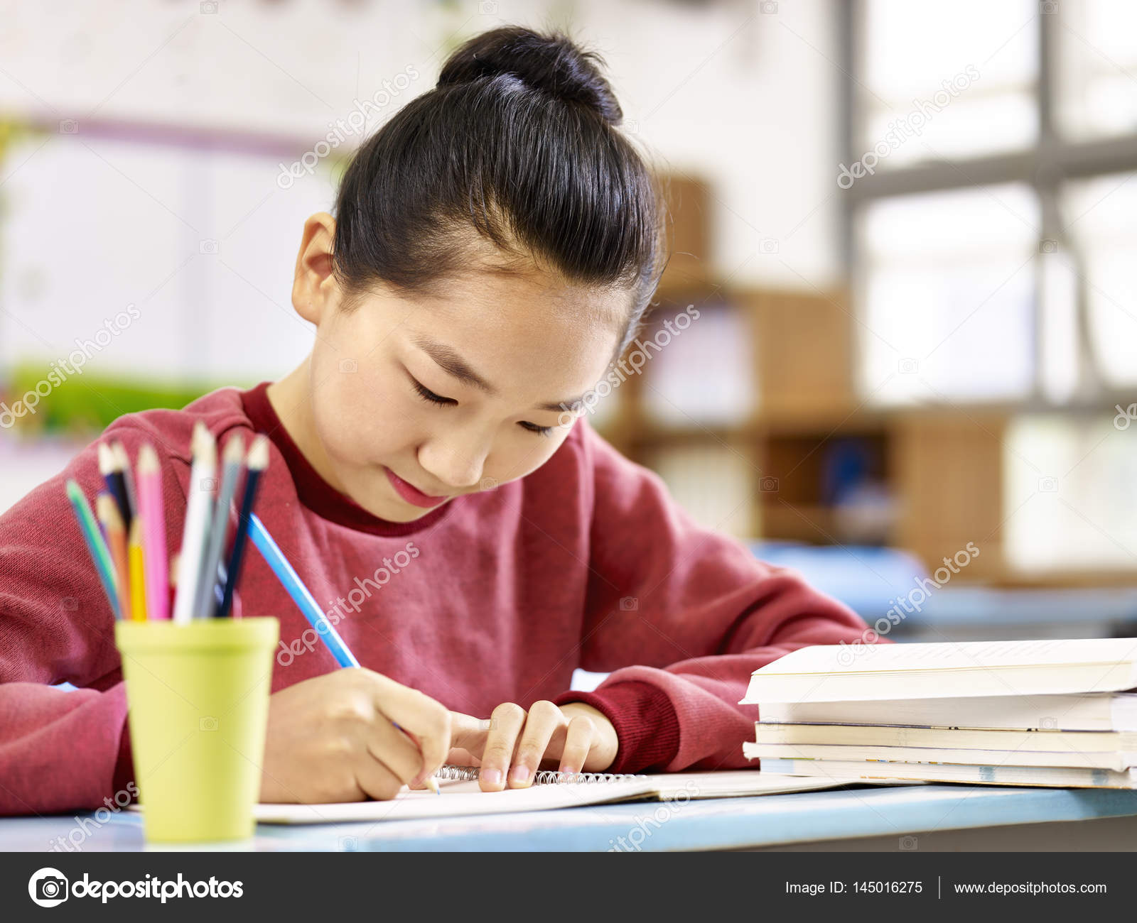 Asian elementary school girl studying in classroom Stock Photo by