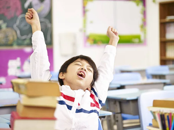 Asian primary school student stretching in classroom — Stock Photo, Image