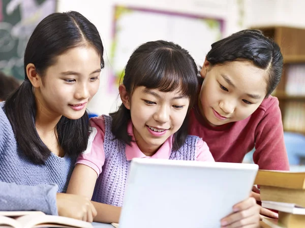 Asiático elementary colegialas usando tableta durante descanso en classr —  Fotos de Stock