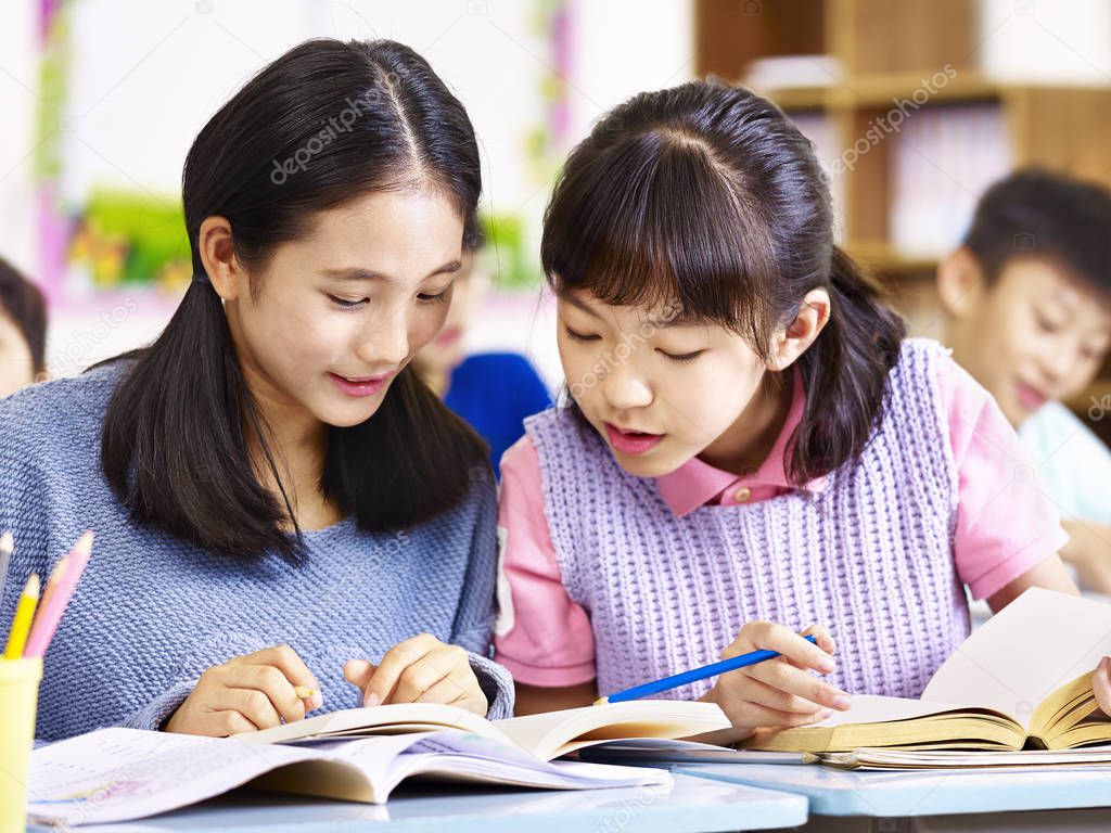 asian elementary school deskmates having a discussion