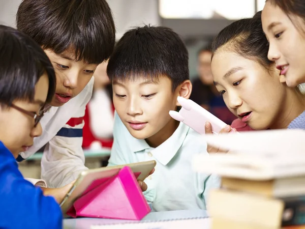 Group of asian primary school pupil playing game using tablet — Stock Photo, Image