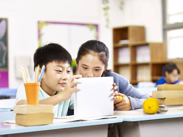 Asiático la escuela primaria chica y escolar usando tableta juntos —  Fotos de Stock