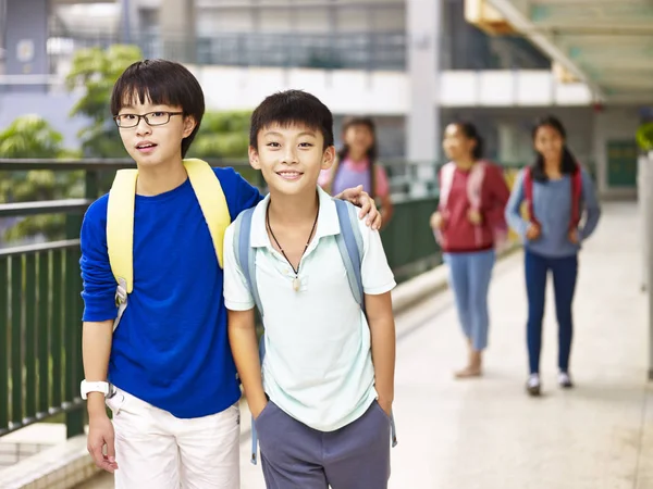 Азиатский ученик начальной школы, идущий по кампусу — стоковое фото