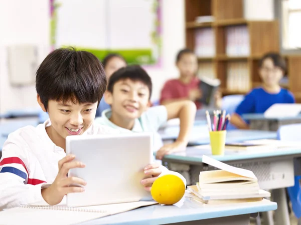 Asiatiska skolpojke använda surfplatta i klassrummet — Stockfoto