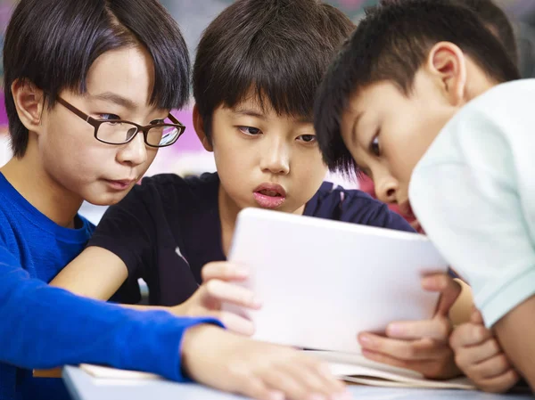 Азиатские младшие школьники используют планшет вместе — стоковое фото