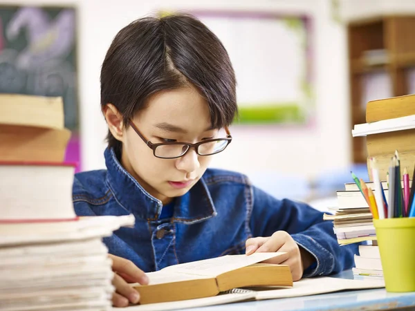 Азиатский младший школьник читает книгу — стоковое фото