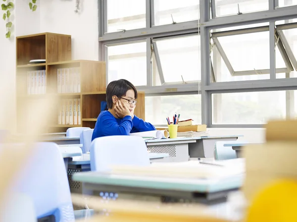 Asiático elemental escolar sentado solo en aula — Foto de Stock