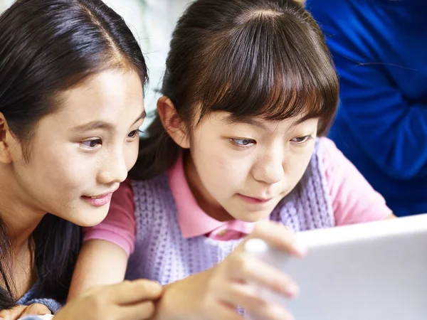 Dos asiático elemental colegialas usando digital tablet juntos —  Fotos de Stock
