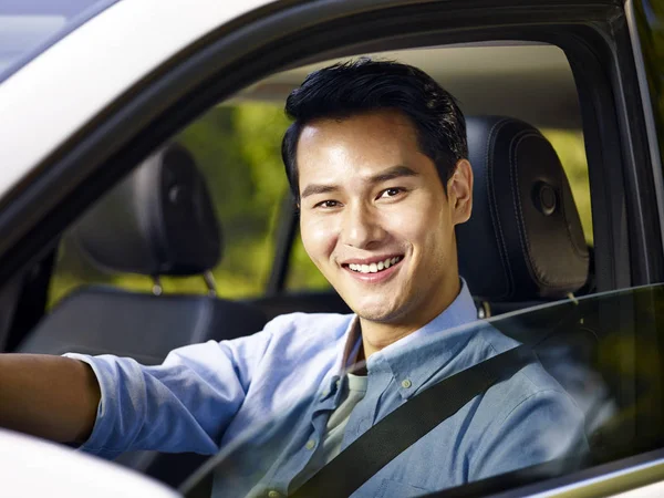 Junger asiatischer Mann sitzt lächelnd im Auto — Stockfoto