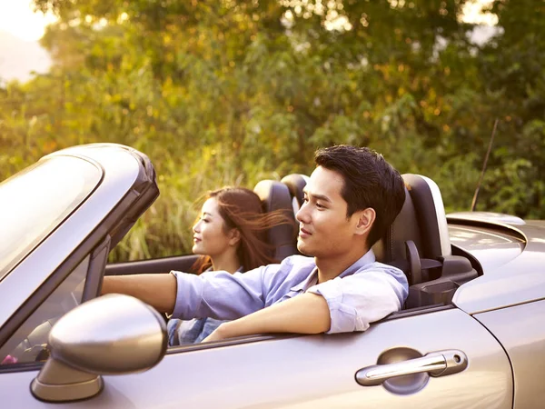 Ungt asiatisk par som kjører i en kabriolet bil – stockfoto