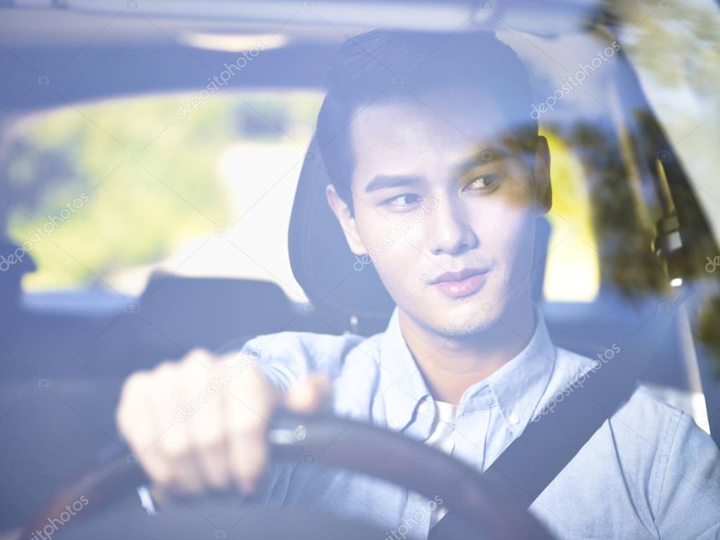young asian man driving a car