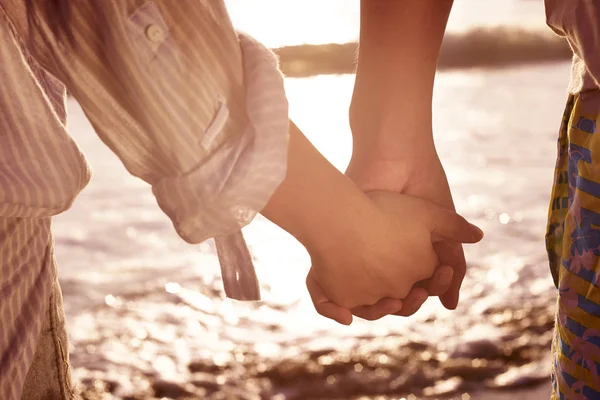 Молодая пара держится за руки на пляже — стоковое фото