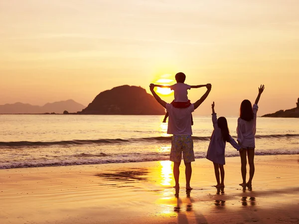 Asiático família assistindo nascer do sol ou pôr do sol na praia — Fotografia de Stock