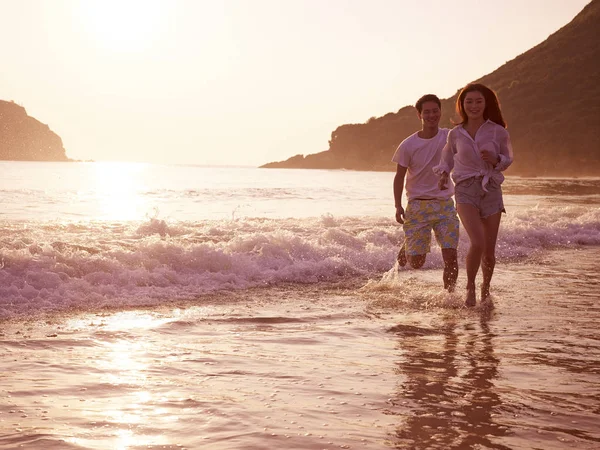 Jovem asiático casal correndo na praia — Fotografia de Stock