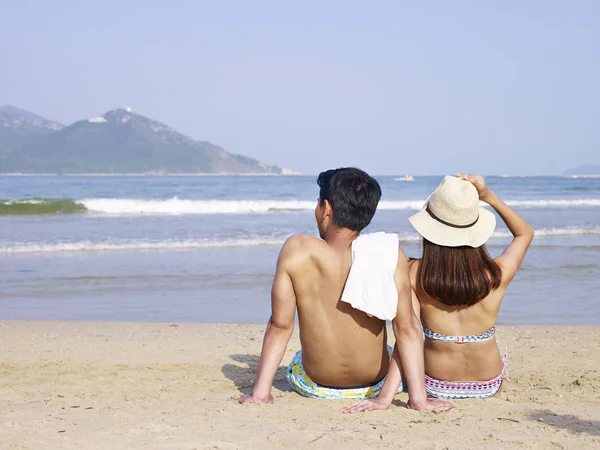 Jóvenes asiático amantes sentado en playa — Foto de Stock