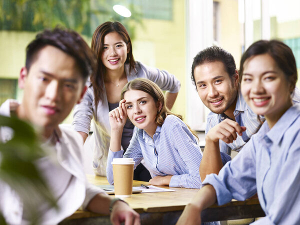 Азиатские и кавказские бизнесмены, работающие вместе в офисе
