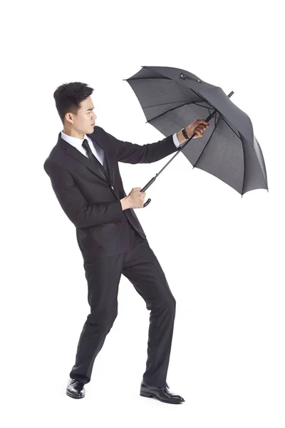 Asian business man holding on to a black umbrella Stock Image