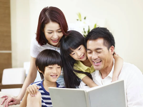 Счастливая семья, читающая книгу дома — стоковое фото