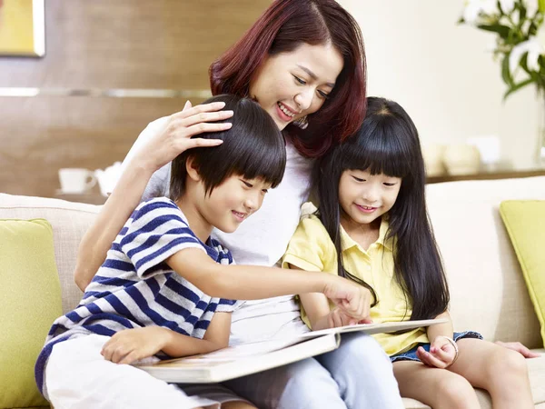 Asian mother and children reading a book together — Stock Photo, Image