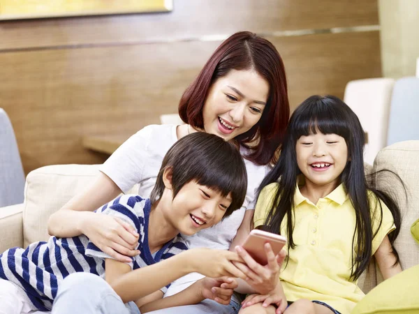 Азиатская мать и дети, использующие мобильный телефон вместе — стоковое фото