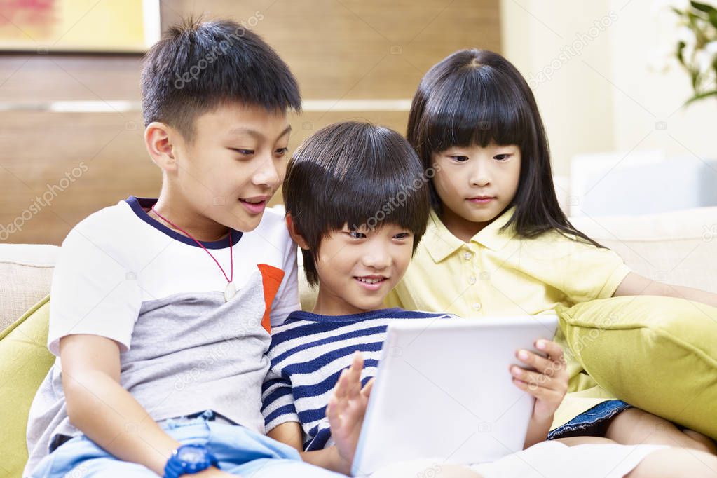 three asian children using digital tablet together