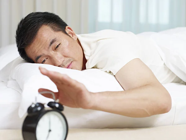 Asiático hombre tratando de detener alarma reloj — Foto de Stock