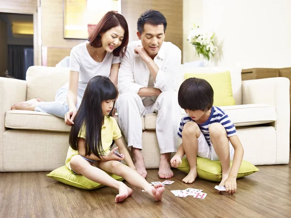 Asiatische Kinder spielen Karten, während Eltern zuschauen — Stockfoto
