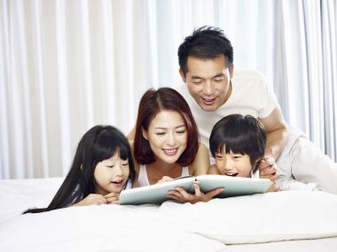 yatakta kitap okuma iki çocuklu Asya aile
